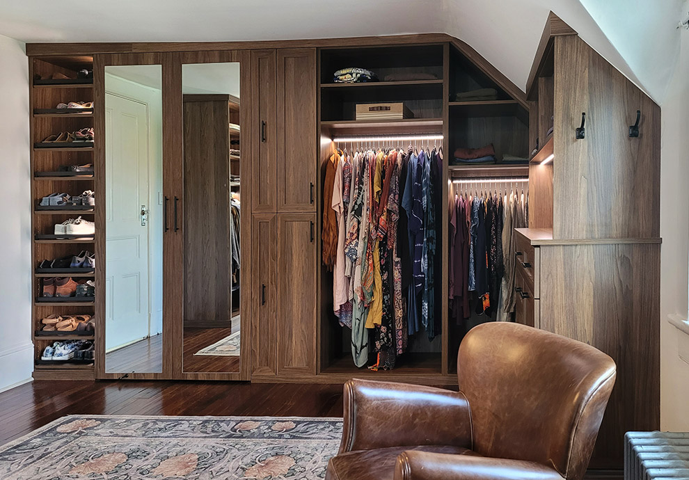 Shared His and Hers Walk-In Closet with Built-In Bureau Cabinet, Lighted Garment Rods, Mirrored Doors and Lighted Shoe Shelves with Fences